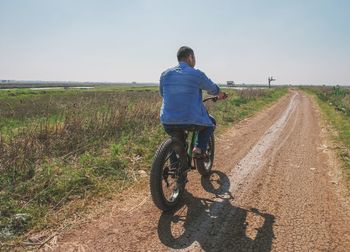 Rear view of man riding bicycle on road