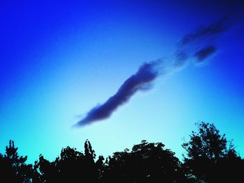 Low angle view of silhouette vapor trail against sky