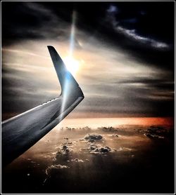 Airplane flying in sky at sunset