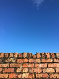 Low angle view of stone wall against blue sky