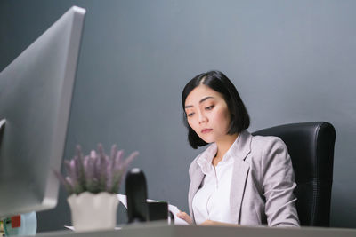 Mid adult woman using mobile phone while sitting on table