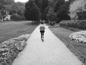 Rear view of woman walking on footpath in park