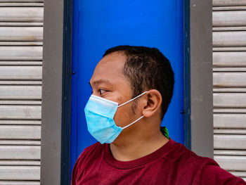 Portrait of boy against blue wall wearing facemask