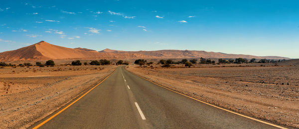 Road amidst desert against sky