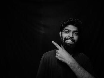 Portrait of young man smoking over black background