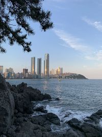 Sea by buildings against sky in city