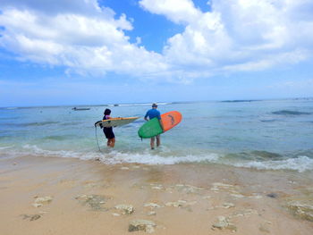 Rear view of men on beach against sky