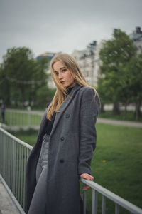 Portrait of woman standing against railing