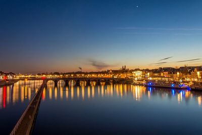 Illuminated bridge over river at night