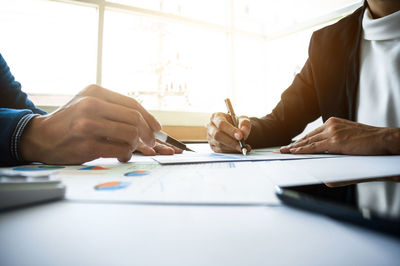 Midsection of man holding paper at table