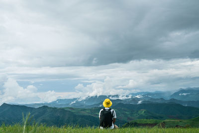 Rear view of man standing on field against sky