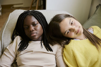 Multiracial female teenager friends lying down while resting at home