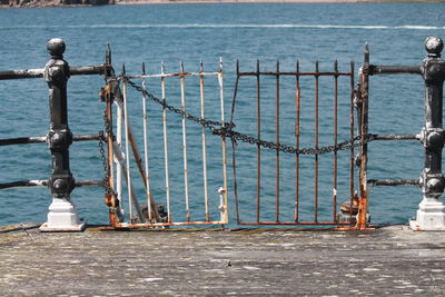 Close-up of metal railing by sea against sky