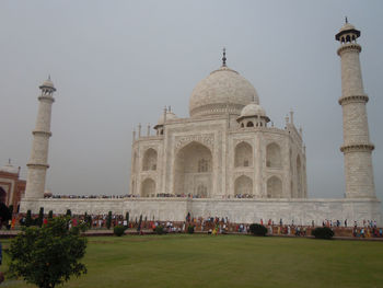 People in front of historical building against clear sky