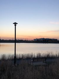 Street light by lake against sky during sunset