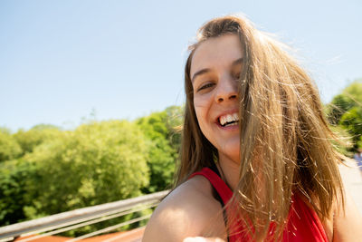 Portrait of smiling young woman against sky