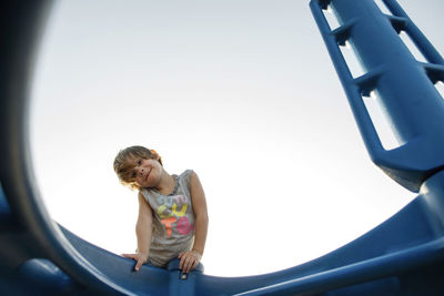 Portrait of girl standing by outdoor play equipment against sky