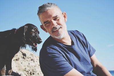 Portrait of man with dog against sky