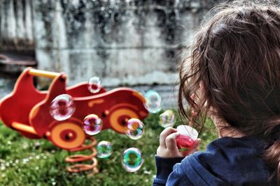 Rear view of girl blowing bubbles at playground