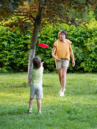 Mother and son play frisbee on grass lawn. outdoor leisure. family life. sports game at backyard.