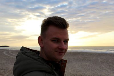 Portrait of man on beach against sky during sunset