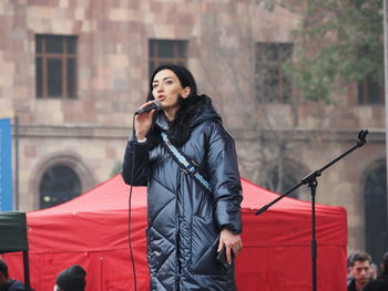 Mid adult woman looking away while standing on mobile phone