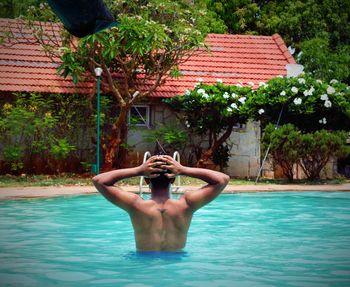 Rear view of shirtless man swimming in pool