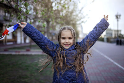 Portrait of happy girl with arms raised