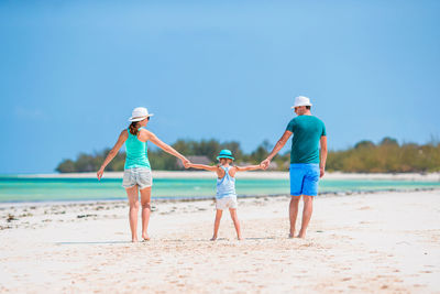 Full length of women on beach against blue sky