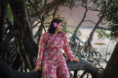 Woman standing by tree trunk