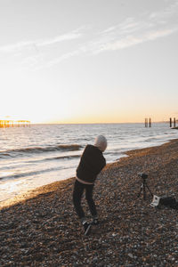 Rear view of man walking at beach against sky