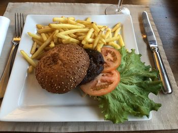 Close-up of fresh burger on table with fries