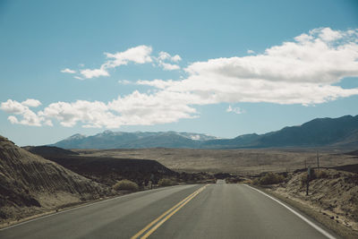 Empty road by mountains against sky