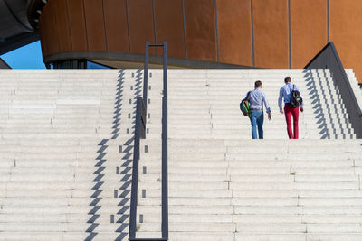 Rear view of men with backpacks climbing staircases