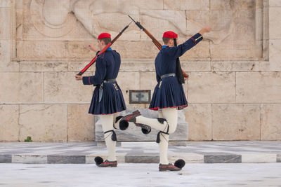 Rear view of women standing against wall