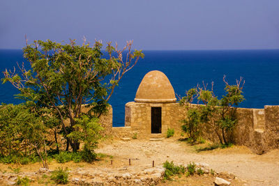 Built structure by sea against clear blue sky