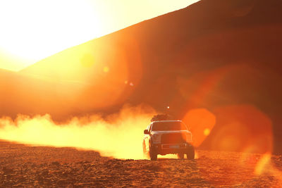 Rear view of vehicle on land against sky during sunset
