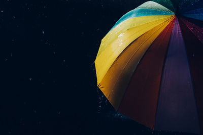 Low angle view of multi colored umbrella against black background