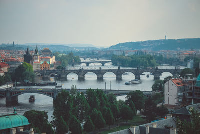 Bridge over river amidst buildings in city against sky