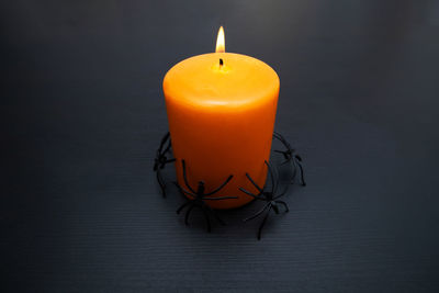 View of burning orange candle with spider around for halloween party with copy space.