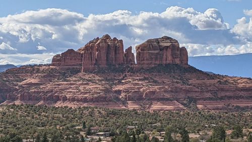 Rock formations on landscape against cloudy sky