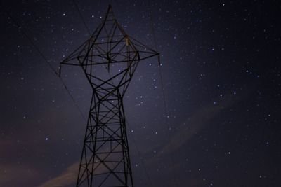Low angle view of electricity pylon against starry sky