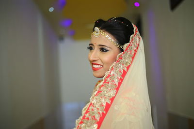 Side view of bride standing by wall in corridor