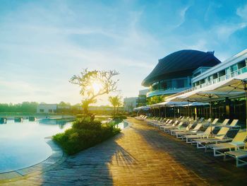 Footpath by swimming pool in city against sky