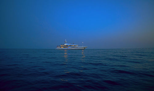 Ship sailing in sea against clear blue sky