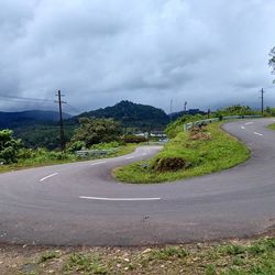 Country road against cloudy sky