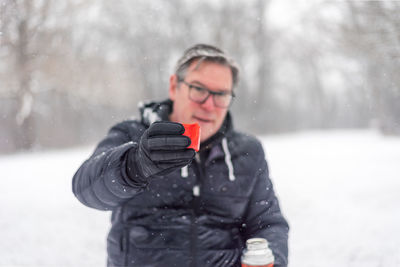 Man holding ice cream standing against snow