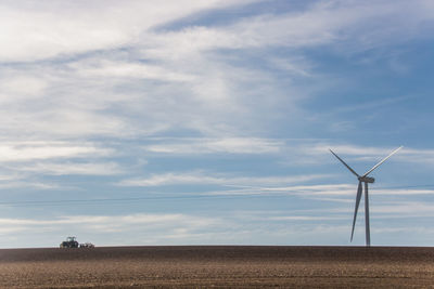 Wind turbines on field against sky