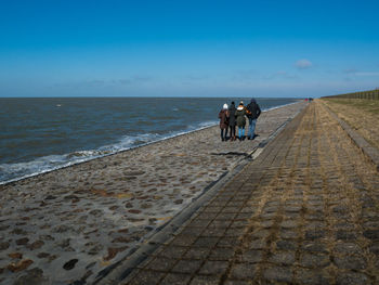 Rear view of people riding motorcycle on sea against sky