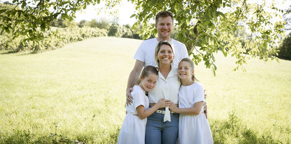 Full length of smiling family standing on field